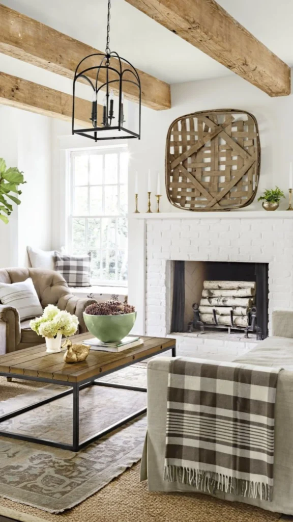 Rustic farmhouse living room with a white painted brick fireplace, large wood tobacco basket, and beige textiles offering cozy home decor ideas.