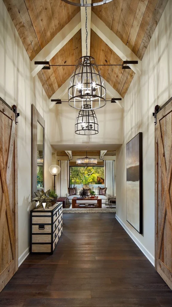 Grand hallway showcasing rustic home decor with sliding wooden barn doors, a vaulted pine ceiling, and a large tiered cage chandelier.