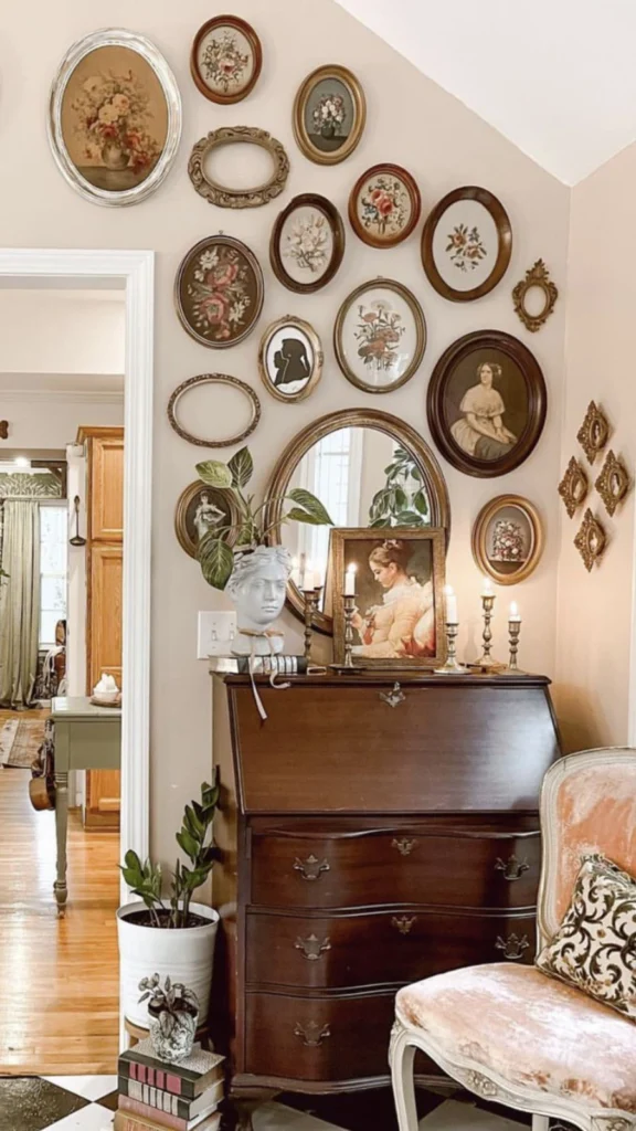 Classic Victorian gallery wall featuring vintage home decor with small oval portrait frames, a wooden secretary desk, brass candlesticks, and a bust planter.