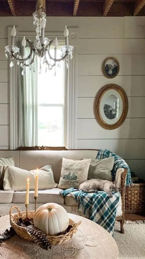 Feminine cottage style mantel displaying vintage home decor with pressed flower art frames, dried pink florals, and a cozy white sofa.