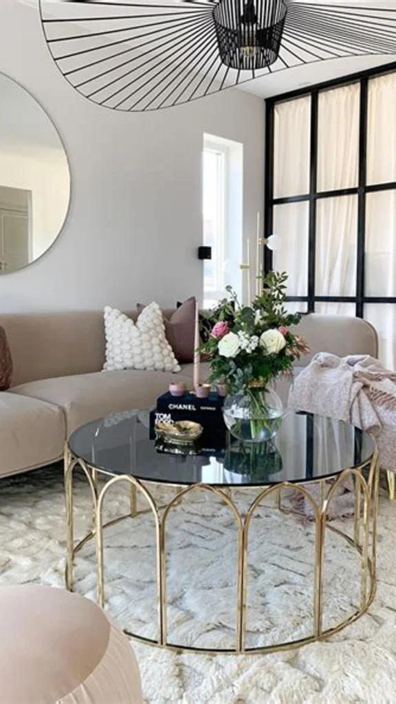 Chic living room featuring round coffee tables with a gold wire-framed glass table, blush pink sofa, and a large black pendant light.