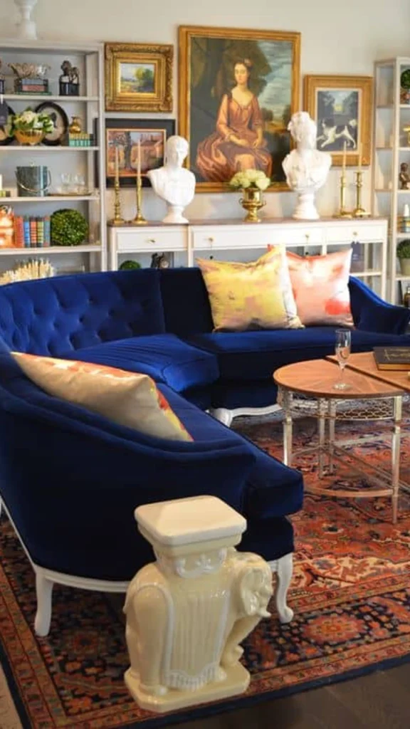 Elegant living room showcasing curved sofas with a deep blue velvet curved sofa, patterned throw pillows, and gold-framed artwork.