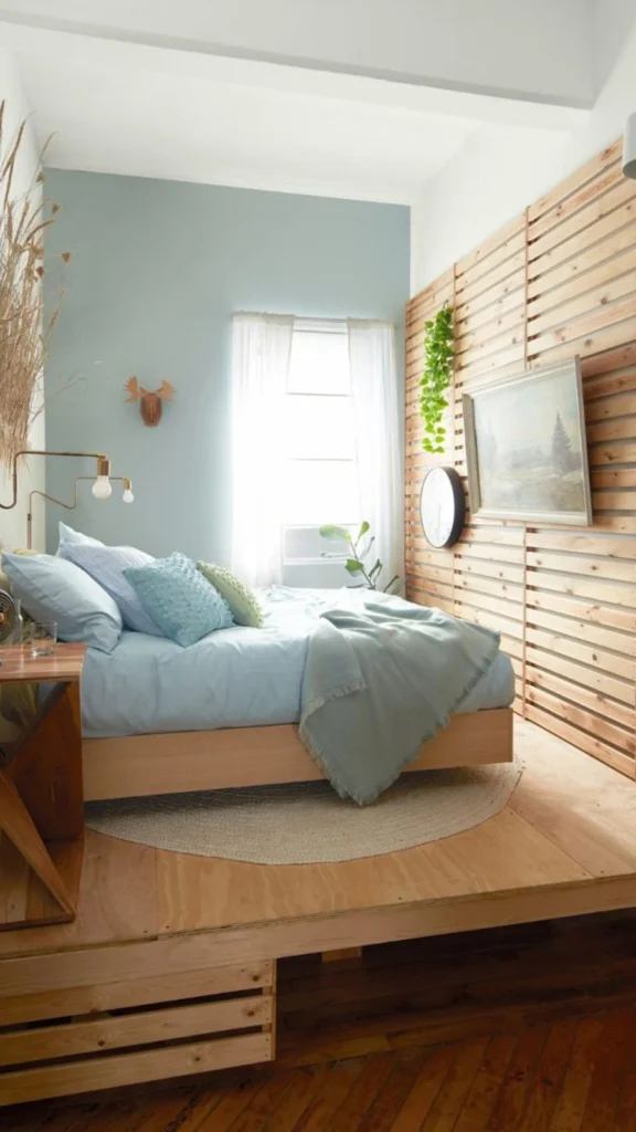 Cozy bedroom featuring Japandi bedroom ideas with a horizontal wood slat accent wall, pale blue bedding, and a raised wooden floor platform.